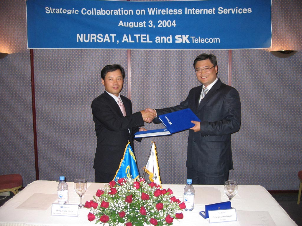 Sung Chul Hong (on left), vice-president and head of SK Telecom`s Global Business Division, Marat Almenbayev (on right), president of NURSAT, are shown signing a contract.